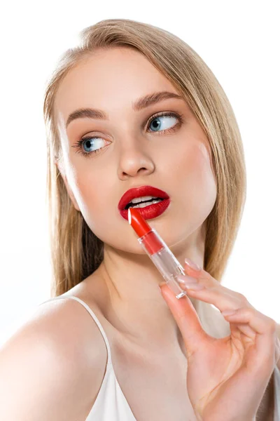 Blonde jeune femme avec des lèvres rouges et les yeux bleus tenant tube de rouge à lèvres isolé sur blanc — Photo de stock