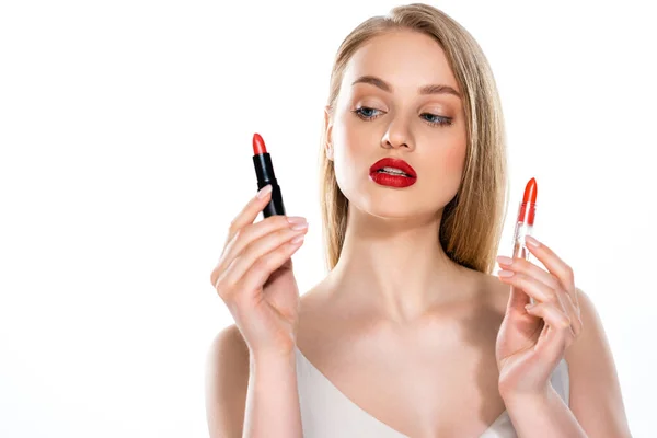 Bonita joven con labios rojos sosteniendo tubos de lápiz labial aislados en blanco - foto de stock