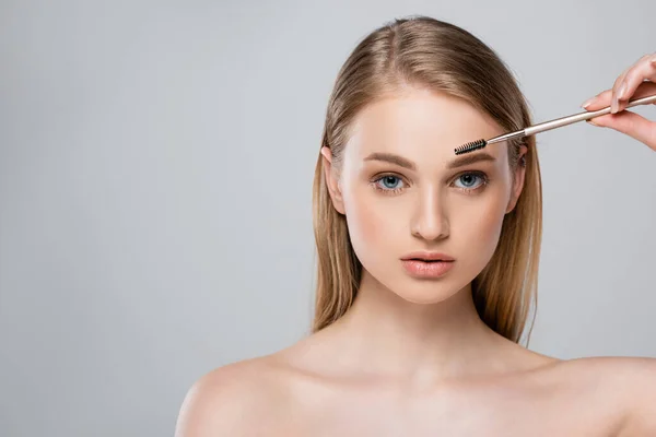 Young woman with bare shoulders styling eyebrow isolated on grey — Stock Photo