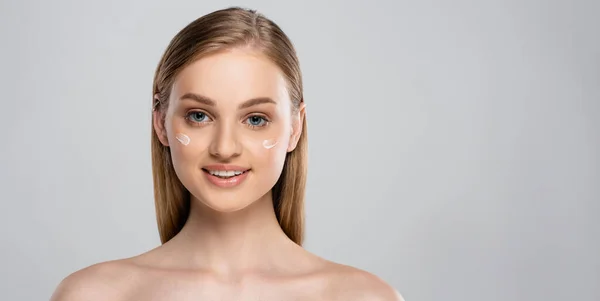 Happy young woman with blue eyes and cream on face isolated on grey, banner — Stock Photo