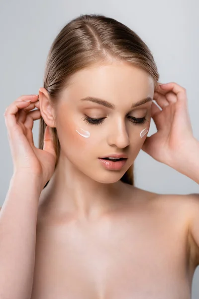 Jeune femme avec crème cosmétique sur le visage isolé sur gris — Photo de stock