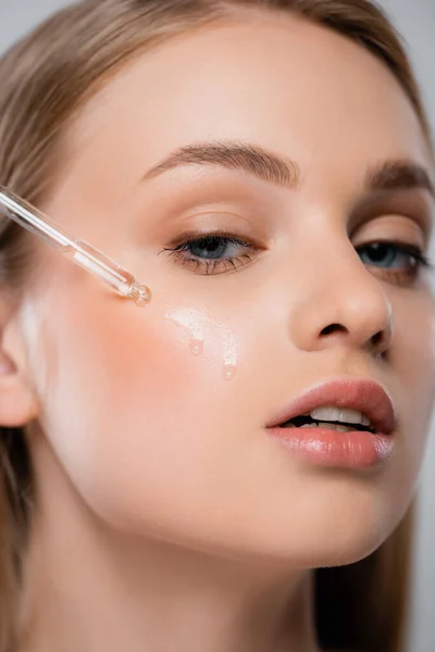 Close up of young woman applying moisturizing serum with pipette — Stock Photo