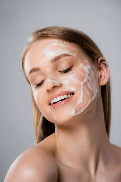 Mulher alegre com olhos fechados e e espuma de limpeza no rosto isolado em cinza — Fotografia de Stock