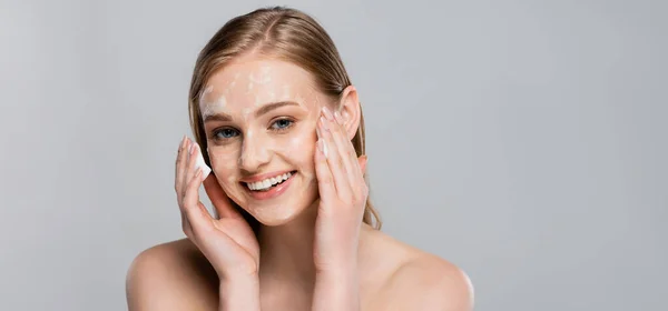 Jovem mulher feliz com olhos azuis e espuma de limpeza no rosto isolado em cinza, banner — Fotografia de Stock