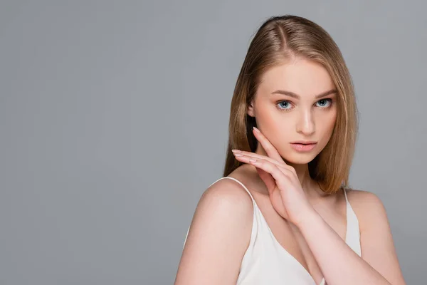 Jeune jolie femme avec maquillage regardant caméra isolée sur gris — Photo de stock