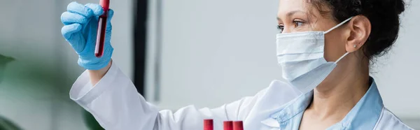 African american scientist in medical mask holding test tube in laboratory, banner — Stock Photo