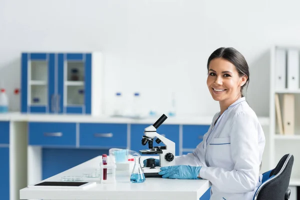 Wissenschaftler lächelt in die Kamera neben digitalem Tablet und medizinischem Gerät im Labor — Stockfoto