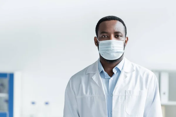 Afrikanischer Arzt mit Schutzmaske steht im Krankenhaus — Stockfoto