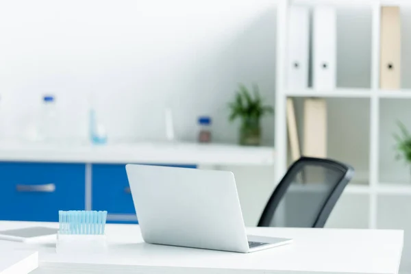 Laptop und Reagenzglas auf dem Tisch im Labor — Stockfoto