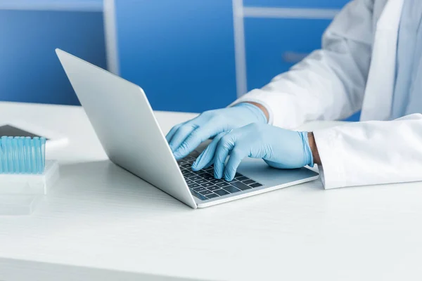 Vista cortada do cientista americano africano usando laptop perto de tubos de ensaio — Fotografia de Stock