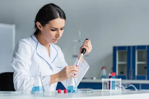 Cientista recolhendo amostra de sangue em pipeta eletrônica no laboratório — Fotografia de Stock