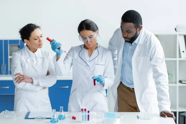 Multiethnic scientist making experiment near equipment in laboratory - foto de stock