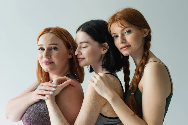 Pretty body positive sportswomen holding hands isolated on grey — Stock Photo