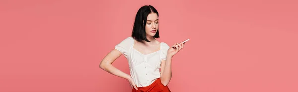 Mujer con estilo con vitiligo sosteniendo teléfono inteligente aislado en rosa, bandera - foto de stock