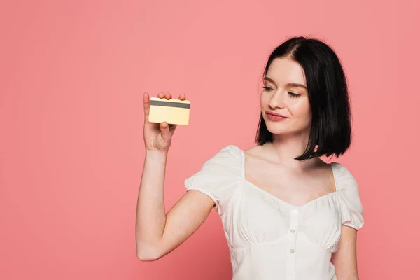 Mujer bonita con vitiligo sosteniendo tarjeta de crédito aislada en rosa - foto de stock