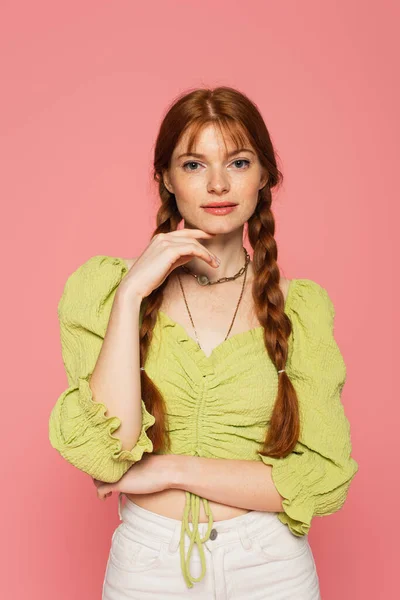 Femme élégante avec des taches de rousseur regardant la caméra isolée sur rose — Photo de stock