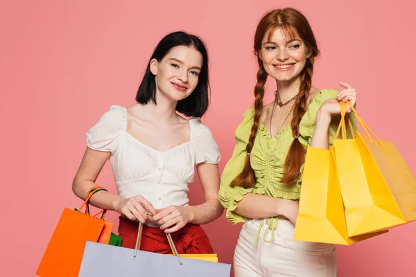 Cuerpo sonriente mujeres positivas sosteniendo bolsas de compras sobre fondo rosa - foto de stock