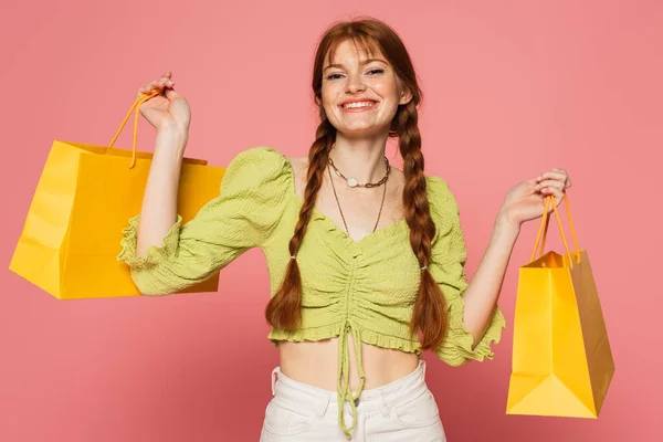 Mulher feliz com sardas na pele segurando sacos de compras isolados em rosa — Fotografia de Stock