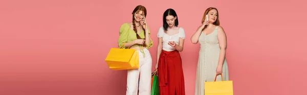 Body positive women with shopping bags talking on smartphones on pink background, banner — Stock Photo