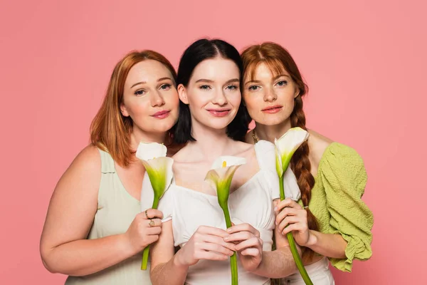 Woman with vitiligo holding calla lily near friends isolated on pink — Stock Photo