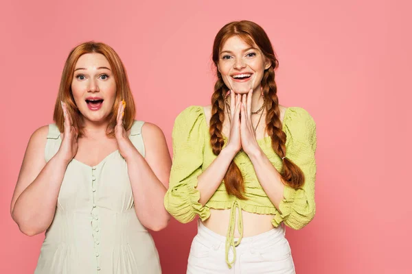 Excited plus size and freckled friends looking at camera isolated on pink — Stock Photo