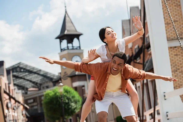 Pareja interracial elegante y alegre divertirse en la calle de la ciudad - foto de stock