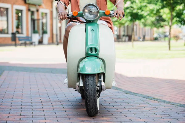 Vista recortada del hombre afroamericano montar scooter en la calle urbana - foto de stock