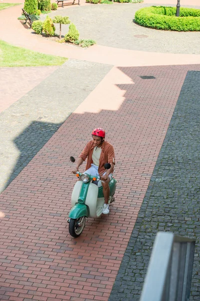 Vista ad alto angolo di uomo africano americano equitazione scooter sulla piazza — Foto stock