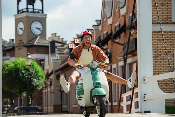 Hombre afroamericano emocionado divertirse mientras monta scooter en la ciudad — Stock Photo