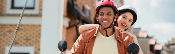 Excited interracial couple riding scooter in city, banner — Stock Photo