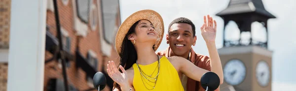 Feliz asiático mulher no palha chapéu aproveitando cidade passeio com africano americano homem, banner — Fotografia de Stock