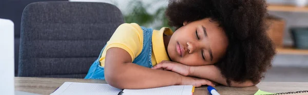 Niño afroamericano durmiendo cerca del cuaderno en casa, pancarta - foto de stock