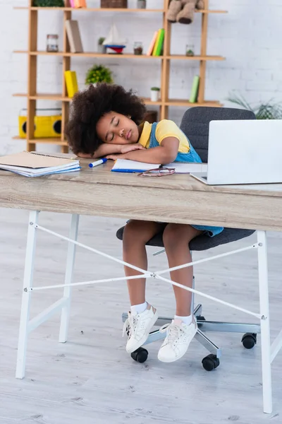 African american kid sleeping near laptop and notebooks on table at home — Stock Photo