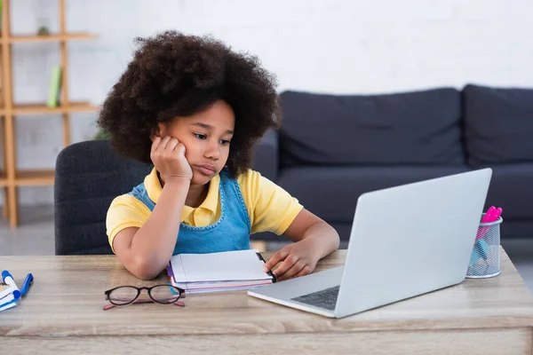 Africano menina americana olhando para laptop durante a educação on-line em casa — Fotografia de Stock