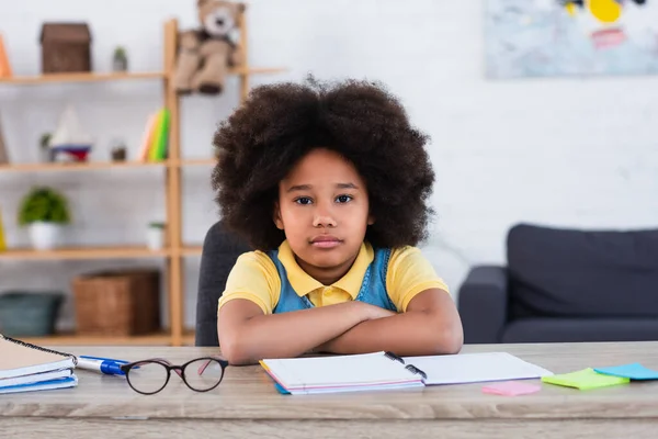 African american kid looking at camera near notebooks and sticky notes at home — Stock Photo