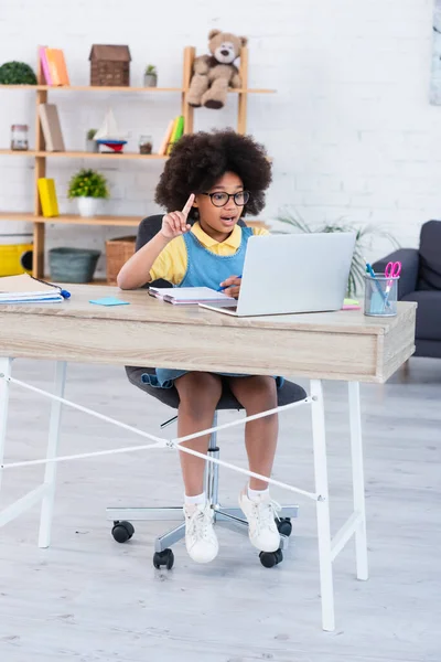 Excited african american kid having idea during online lesson on laptop at home — Stock Photo