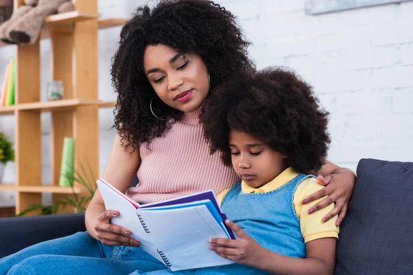 African american woman hugging kid with notebook — Stock Photo