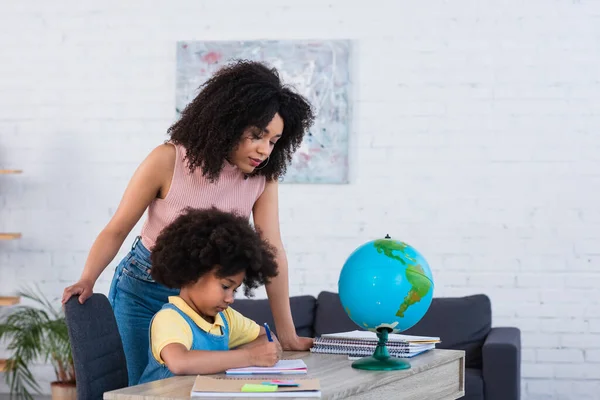 Un parent afro-américain aide sa fille à travailler à la maison — Photo de stock