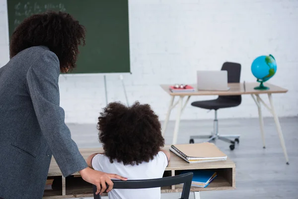 African american teacher standing near pupil in classroom — Stock Photo