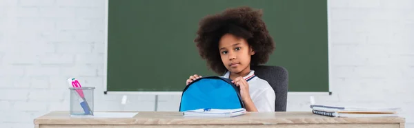 Африканський американець, що тримає рюкзак і дивиться на камеру в класі, банер. — Stock Photo