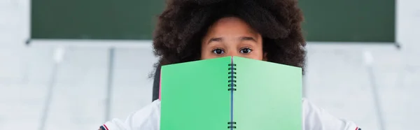 Afro-américaine écolière couvrant visage avec ordinateur portable, bannière — Photo de stock