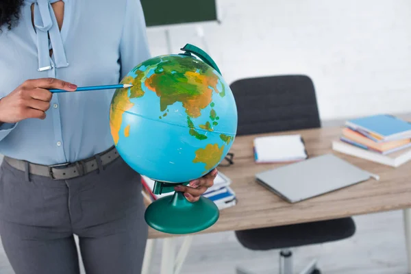 Cropped view of african american teacher pointing at globe with pencil — Stock Photo