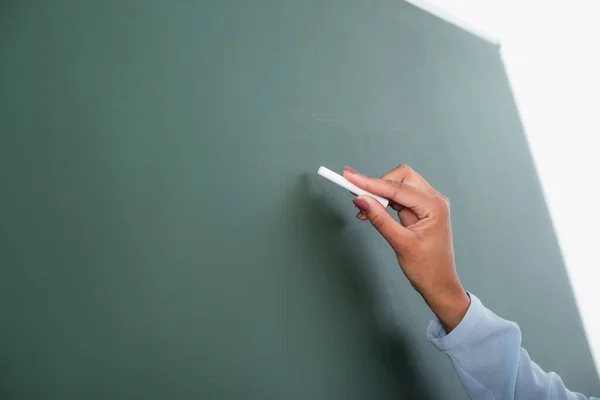 Cropped view of african american teacher writing on chalkboard — Stock Photo
