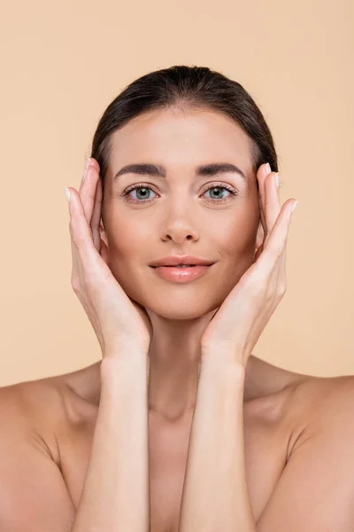 Front view of brunette woman with hands near perfect face isolated on beige, beauty concept — Stock Photo