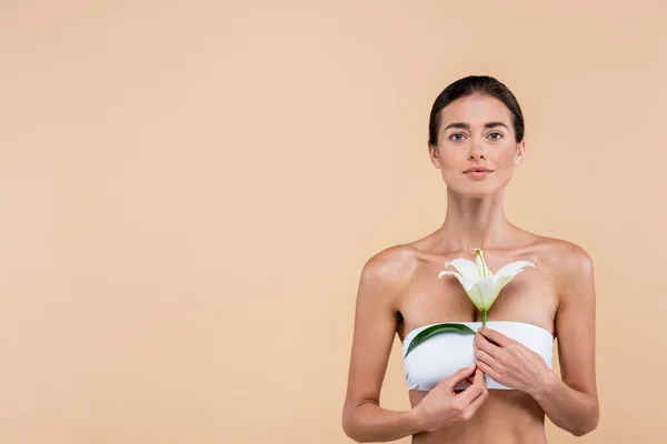 Young woman in strapless top holding white lily flower isolated on beige, beauty concept — Fotografia de Stock