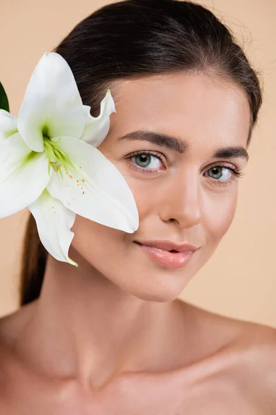 Primer plano retrato de mujer bonita cerca de lirio blanco aislado en beige, concepto de belleza — Stock Photo