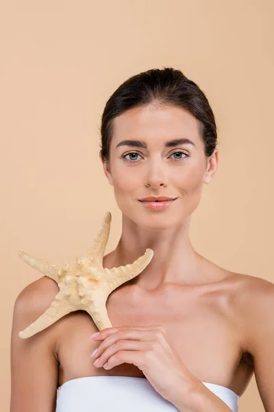 Giovane donna con pelle perfetta con stelle marine isolate sul beige, concetto di bellezza — Foto stock
