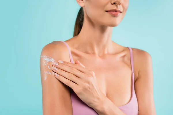 Cropped view of young woman applying sunscreen isolated on blue — Stock Photo