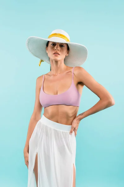 Young woman in straw hat and pareo posing with hand on hip isolated on blue, beauty concept — Fotografia de Stock