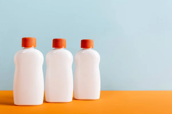 White bottles of sunblock on orange surface isolated on blue — Stock Photo